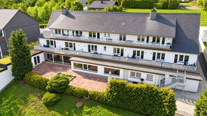 Un immeuble résidentiel de deux étages, doté d’un balcon à chaque étage, d’un patio couvert et d’un jardin bien entretenu.
