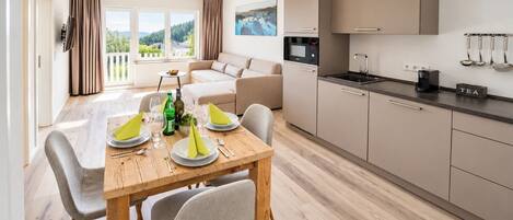 Una cocina moderna con comedor, sofá y vista a zonas verdes.