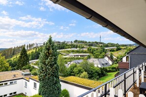 Zona residencial con casas, un gran árbol de coníferas y una torre de línea eléctrica a lo lejos.