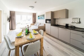 Una cocina moderna con comedor, mesa de madera y armarios de color claro.