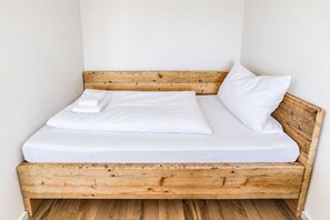 Un lit simple avec une tête de lit en bois et du linge de lit blanc.