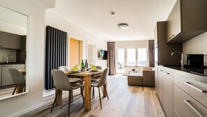 A modern apartment with a dining area, kitchen, and living space. - Smart Resorts - House Diamant - Apartment 705 with balcony, max. 5 persons - (Winterberg)