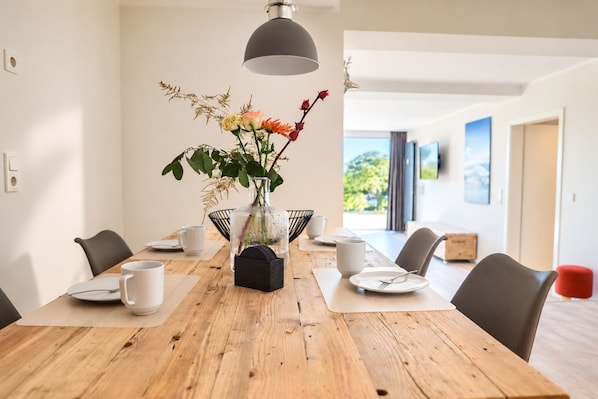 A dining table with chairs, a vase with flowers, and a pendant light.