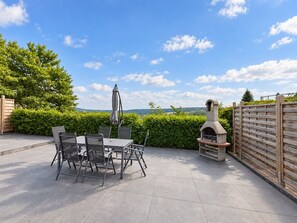 Un patio exterior con una mesa y sillas, una parrilla y vistas al campo.