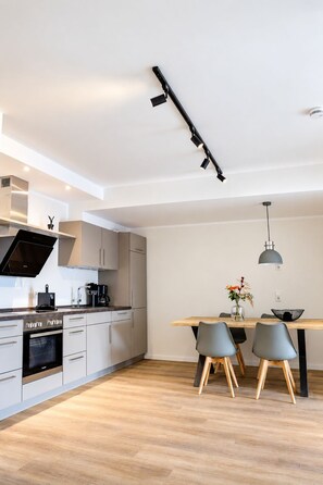 Una cocina moderna con comedor, que presenta una mesa de madera, dos sillas y una lámpara colgante.