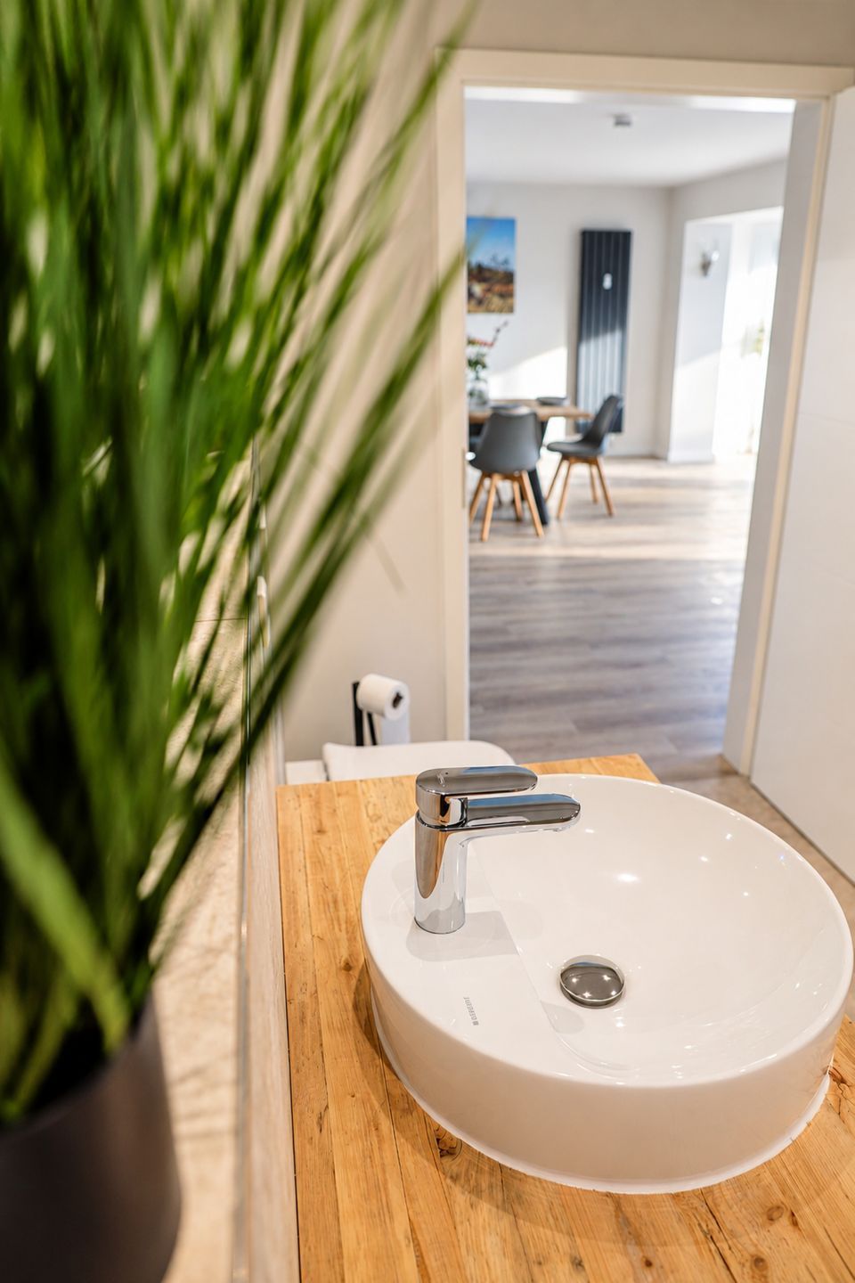 A bathroom with a white sink, chrome faucet, and a wooden countertop.