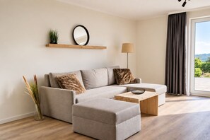 Una sala de estar moderna con un sofá, una mesa de centro y vistas al exterior.