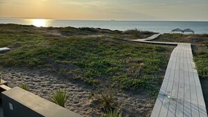 En strand med en træpromenade, der fører til et sideskur.
