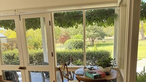 A room with a wooden floor, a dining table with chairs, a sofa, and a large window with a view of a garden. - The Convent O”Connell Circa 1867 cosy, charming, character filled retreat (O'Connell)