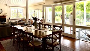 A spacious living room with a large wooden dining table, comfortable seating, and a view of a garden through glass doors. - The Convent O”Connell Circa 1867 cosy, charming, character filled retreat (O'Connell)