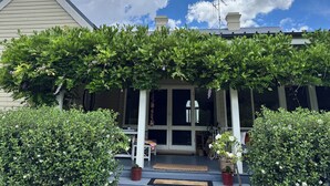 A house with a covered porch, a chimney, and a large window. - The Convent O”Connell Circa 1867 cosy, charming, character filled retreat (O'Connell)
