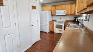 Eine Küche mit Holzschränken, einem weißen Kühlschrank, einer Mikrowelle und einem Herd.
