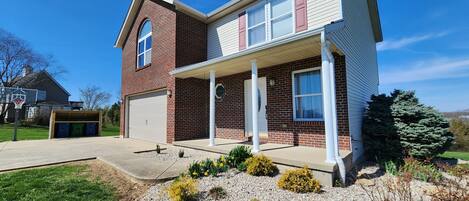 A two-story house with a brick exterior, a garage, and a covered porch.