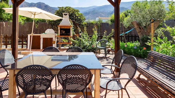 An outdoor patio with a table and chairs, a barbecue grill, and a pergola with a hanging lantern. - Cottage with pool, barbecue and garden (Nigüelas)