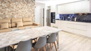 A modern kitchen with white cabinets, a black countertop, and a stone wall. - Cottage with pool, barbecue and garden (Nigüelas)
