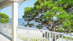 Un balcon avec une balustrade blanche donnant sur une plage et un pin.