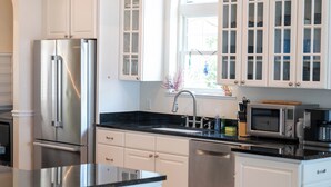 Une cuisine moderne avec des meubles blancs, des appareils en acier inoxydable et un grand îlot central.