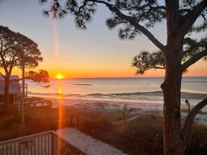 A beach view with a sunset, a wooden deck, and a building with a balcony. - 🏖️Beachfront🏖️ Forget your worries in this spacious and serene space ♡ (Alligator Point)