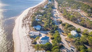 Une vue aérienne d’une zone côtière avec une plage, des maisons et des routes.