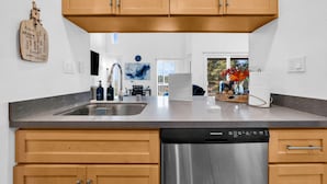 Una cucina moderna con mobili in legno, una lavastoviglie in acciaio inossidabile e un piano di lavoro in granito.