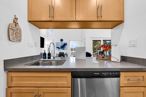 Una cocina moderna con armarios de madera, lavavajillas de acero inoxidable y encimera de granito.