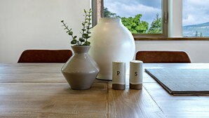 Una mesa de madera con un florero, dos saleros y un mantel individual.