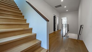 Un interior moderno con una escalera de madera, paredes blancas y suelo de madera.