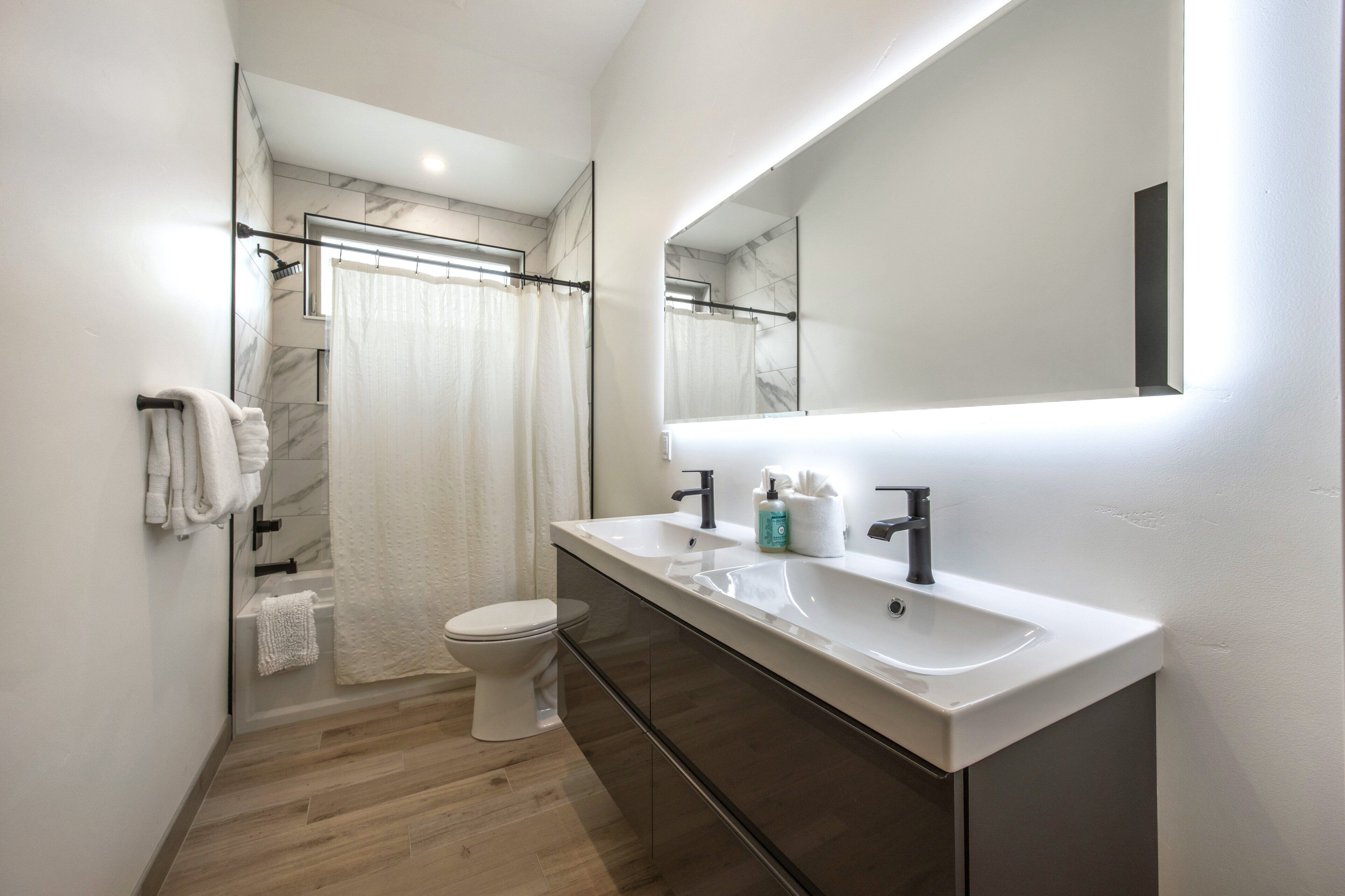 A modern bathroom with a dual sink vanity, a toilet, and a shower area.