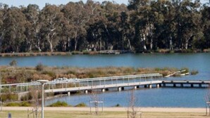 Un pont enjambant un lac, avec des arbres en arrière-plan.