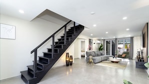 Ein modernes Wohnzimmer mit einer schwarzen Treppe, einem grauen Sofa und einem Couchtisch.