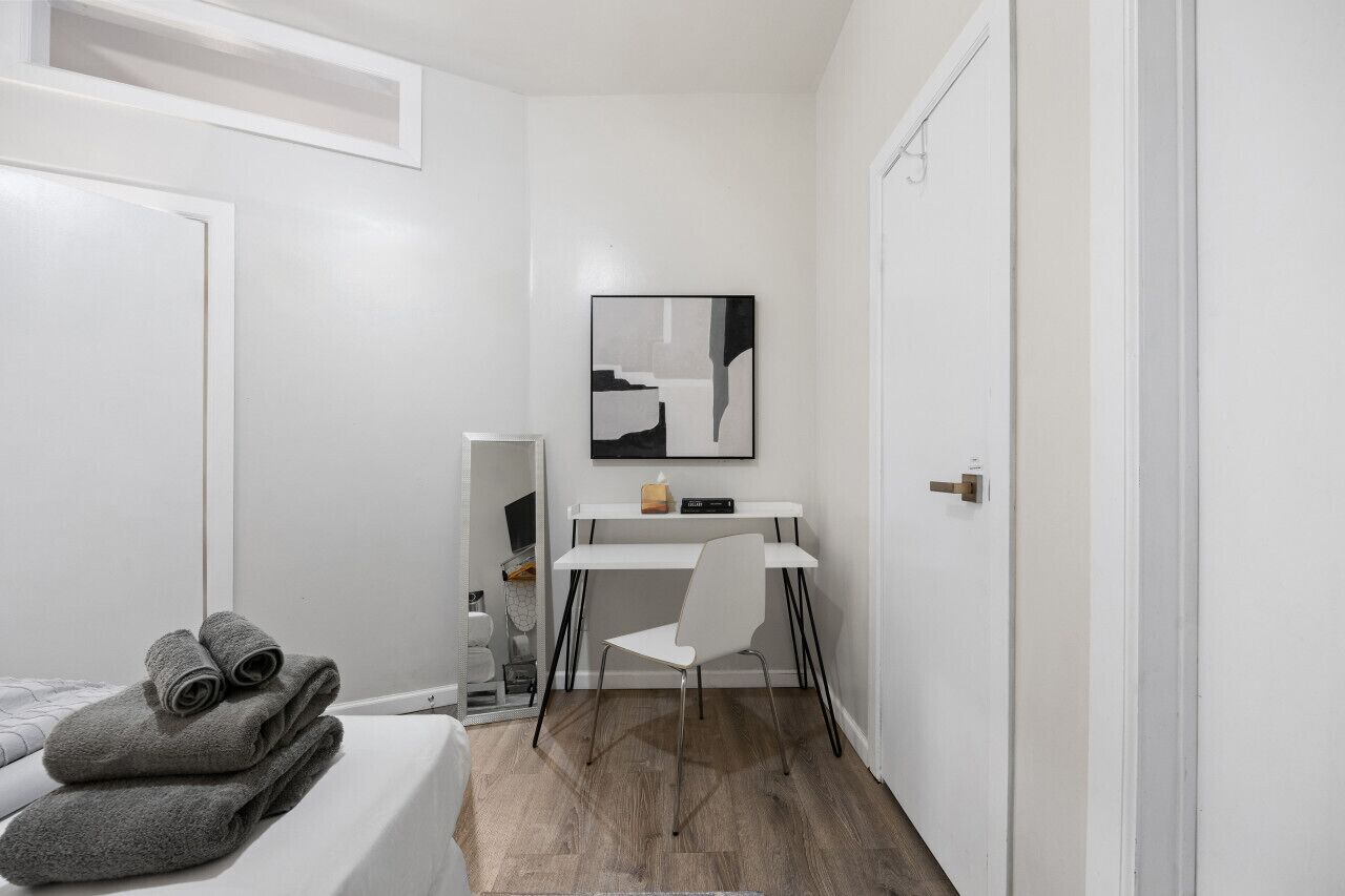 A small, modern bedroom with a bed, a desk, and a chair.