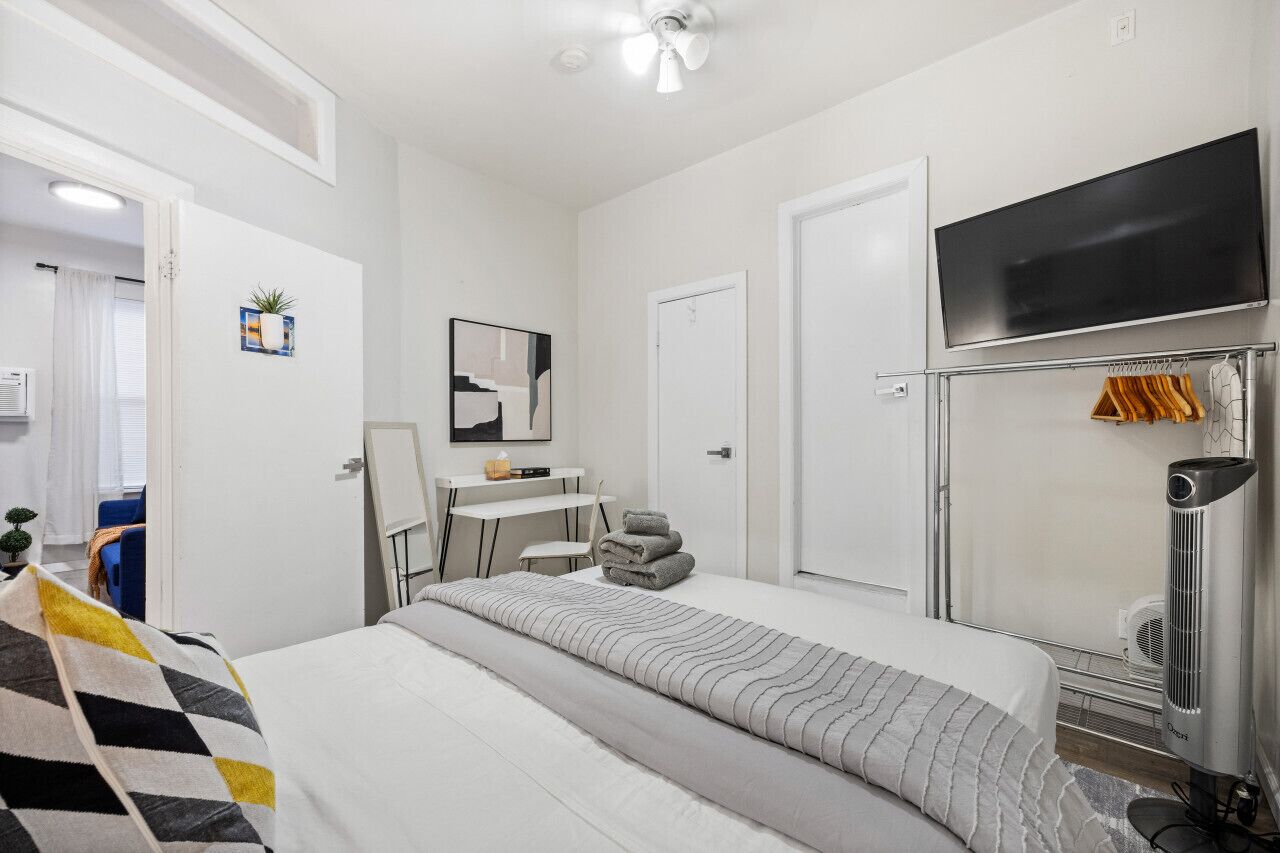 Una habitación de hotel moderna con cama, escritorio, silla, televisor y calentador.