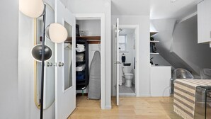 A modern, compact room with a walk-in closet, a small kitchenette, and a dining area with a glass table. - Studio Near Restaurants, Broadway, & Shopping (New York)