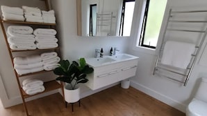 Un baño moderno con suelo de madera, lavabo blanco y un perchero para toallas.