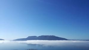 Una cordillera con cielo despejado arriba y una capa de niebla o bruma en la base.