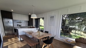 Una cocina moderna con una isla grande, suelo de madera y una zona de comedor con mesa y sillas.