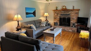 A living room with a grey sofa, two lamps, a fireplace, and a television.