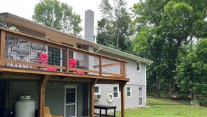A two-story house with a covered patio, a chimney, and a fenced balcony with chairs.