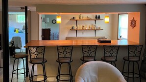 A kitchen with a wooden island, bar stools, and shelves with decorative items.