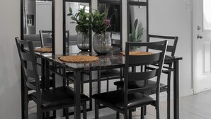 Un comedor con una mesa rectangular, sillas negras y un centro de mesa con planta decorativa.