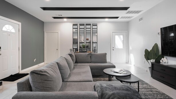 Una sala de estar moderna con un sofá modular, una mesa de centro y un televisor sobre un mueble.