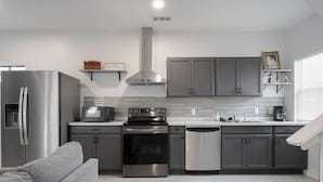 Una cocina moderna con armarios grises, electrodomésticos de acero inoxidable y un sofá gris.
