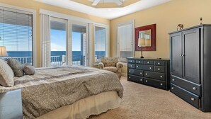 A bedroom with a large bed, a dresser, a chair, and a ceiling fan. - Sea Monster, West. Big. Beachfront. Pool. Sleeps 26. Awesome location! (Gulf Shores)