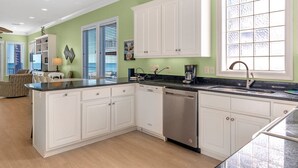 A modern kitchen with white cabinetry, a dishwasher, and a large window with frosted glass. - Sea Monster, West. Big. Beachfront. Pool. Sleeps 26. Awesome location! (Gulf Shores)
