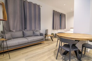 Un salon moderne avec un canapé gris, une table basse en bois et des rideaux gris.