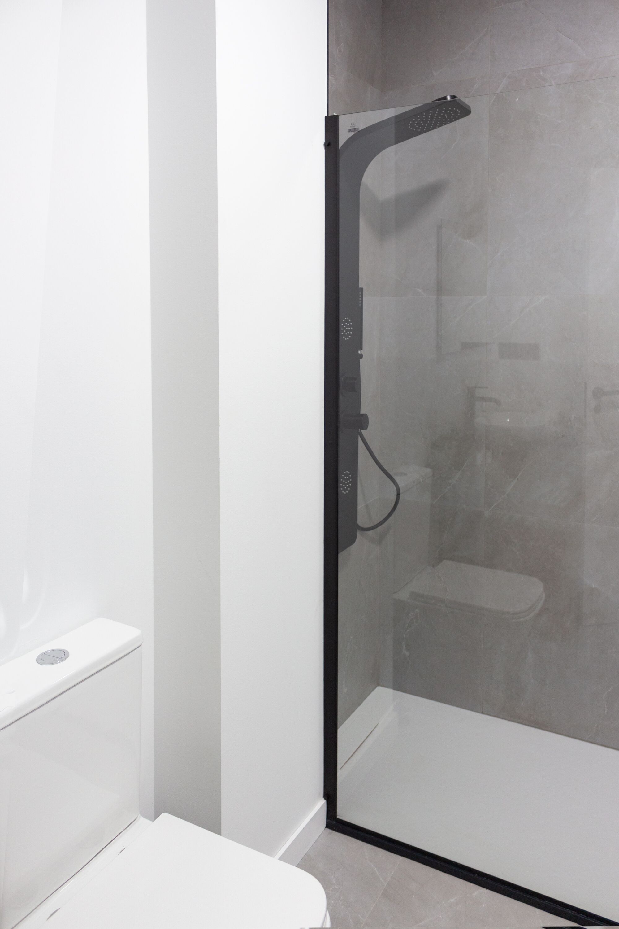 A modern bathroom with a glass-enclosed shower, a white toilet, and a white sink.