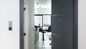 A modern hallway leading to a dining area with a view of the cityscape.