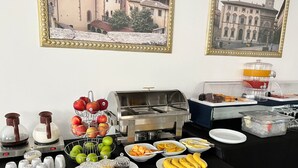 Un bufé de desayuno con diferentes alimentos y bebidas, incluyendo frutas, jugos y una estación de café.