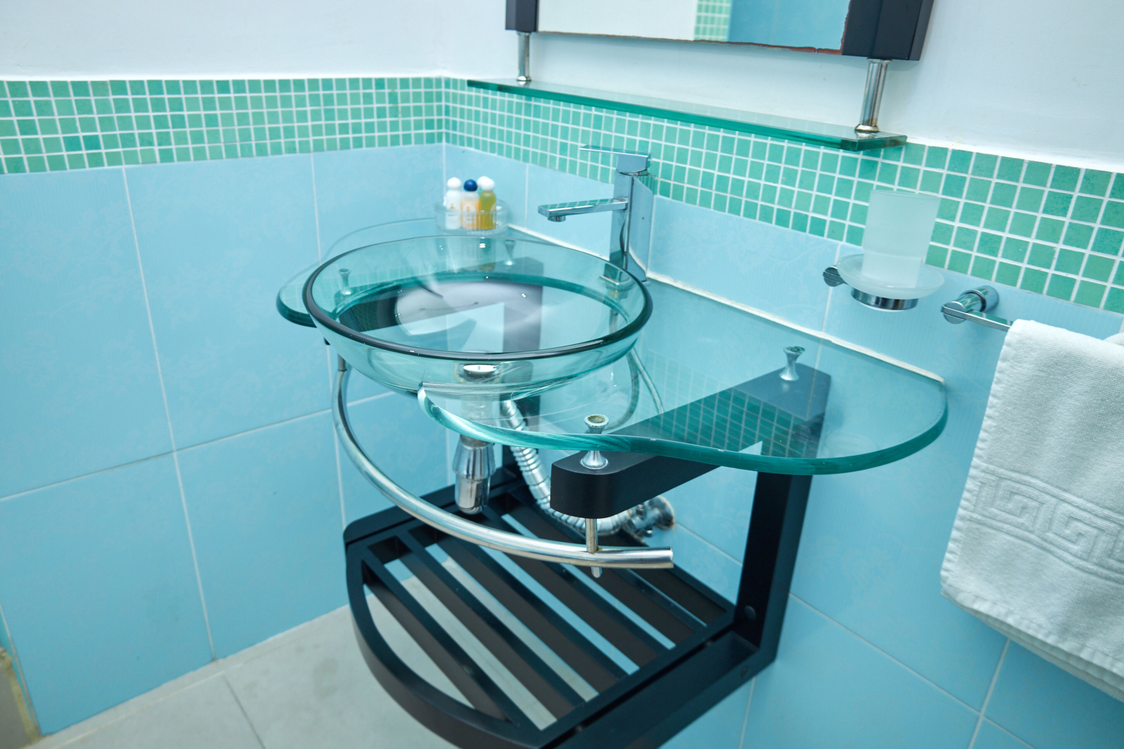 Une salle de bain avec un lavabo en verre, un porte-serviettes et un miroir.
