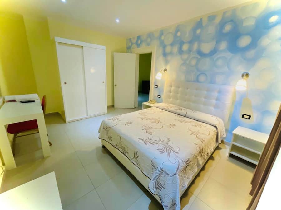 A bedroom with a bed, a desk, and a wardrobe.